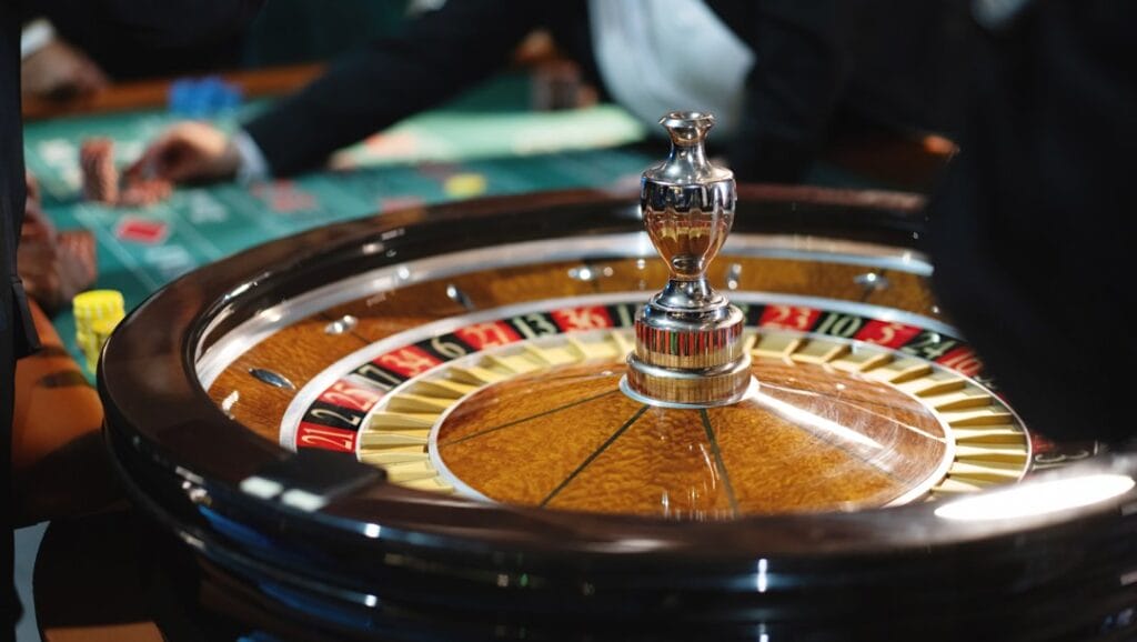 A close-up of a roulette wheel with the roulette table behind it.