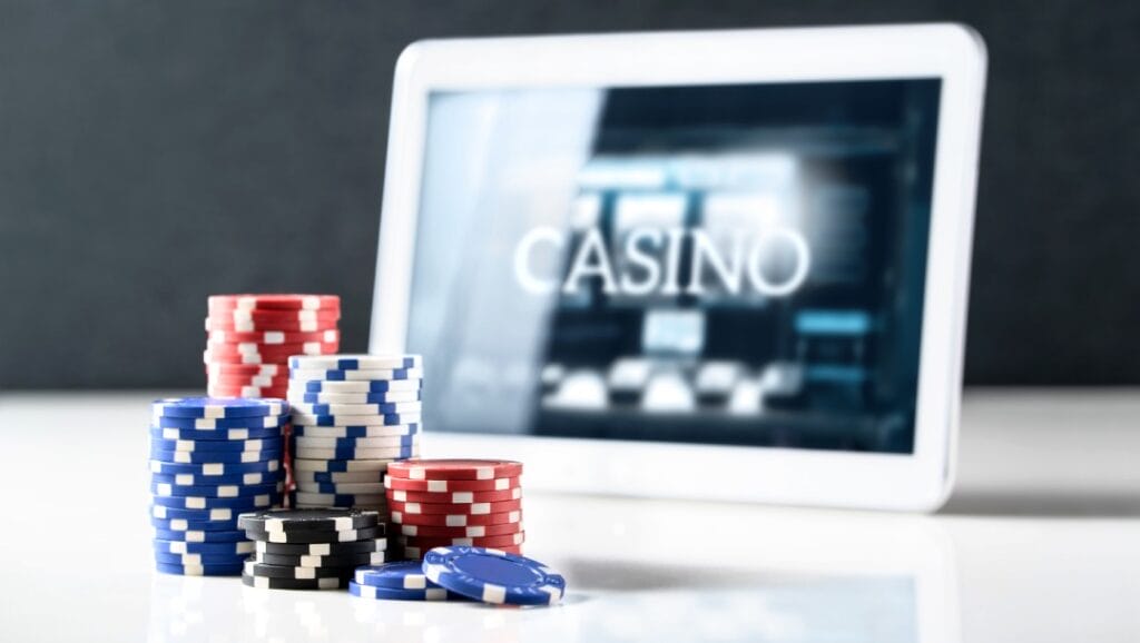 A white smartphone with an online casino display. There are casino chips on a white table.